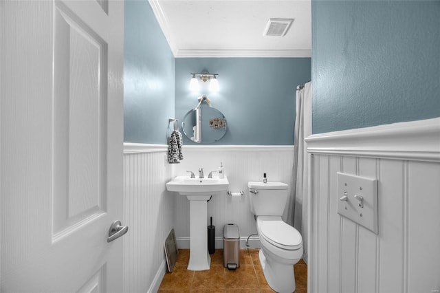 bathroom featuring toilet, tile patterned floors, visible vents, and wainscoting