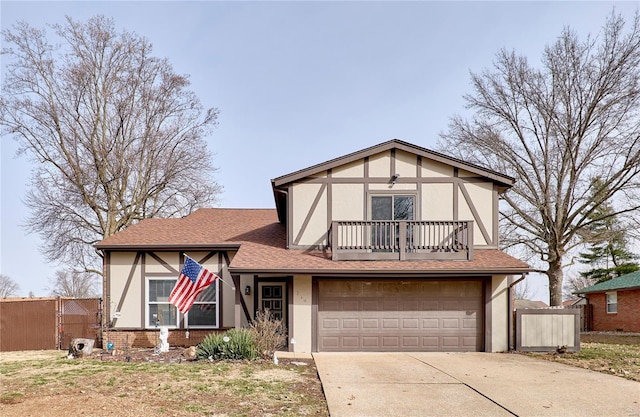 tudor home with a balcony, a garage, brick siding, fence, and concrete driveway