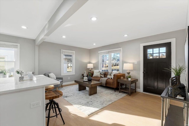 living room featuring baseboards, beam ceiling, light wood-style flooring, and recessed lighting