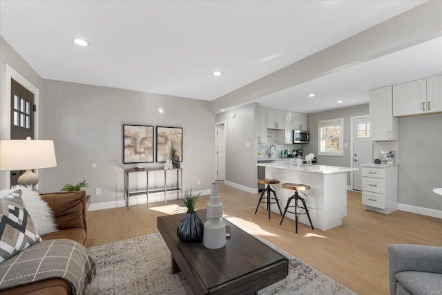 living area with light wood-type flooring, baseboards, and recessed lighting