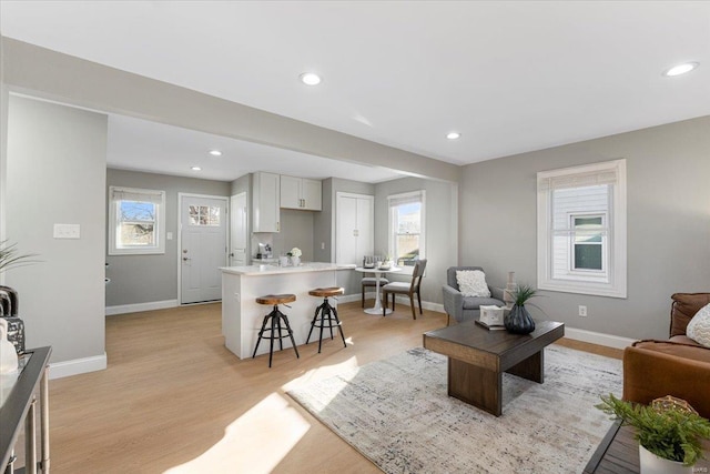 living room with light wood finished floors, recessed lighting, and baseboards