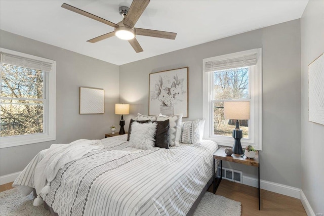 bedroom with visible vents, ceiling fan, baseboards, and wood finished floors