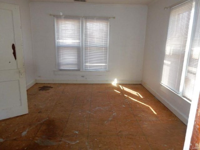 empty room featuring a wealth of natural light and baseboards