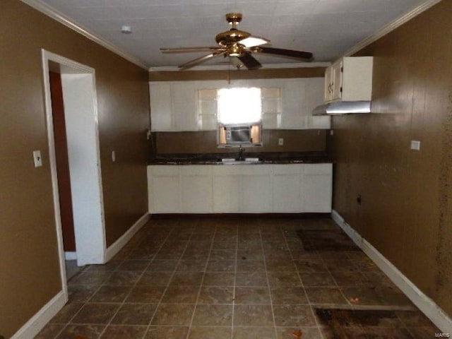 kitchen featuring dark countertops, ceiling fan, crown molding, white cabinetry, and a sink