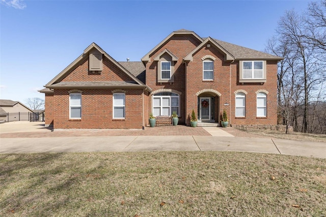 view of front of property with a shingled roof, a front yard, and brick siding