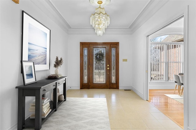 foyer featuring a chandelier, crown molding, and baseboards