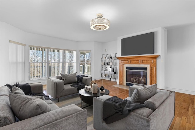 living room featuring a fireplace with flush hearth, wood finished floors, and baseboards