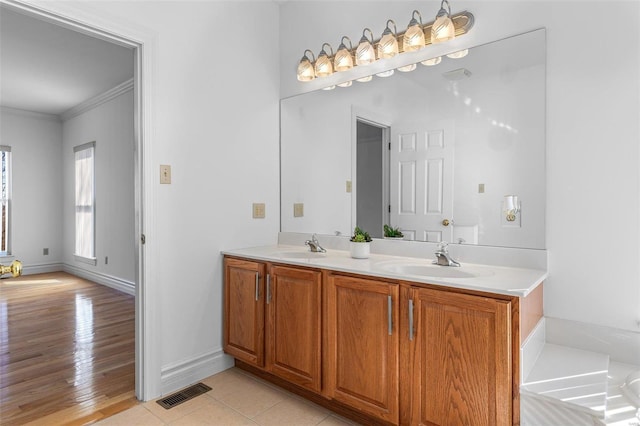 bathroom with double vanity, visible vents, ornamental molding, a sink, and baseboards