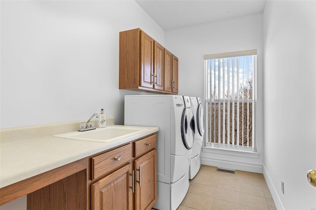 clothes washing area with cabinet space, visible vents, a sink, independent washer and dryer, and baseboards