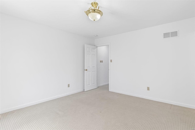 spare room featuring light carpet, visible vents, and baseboards