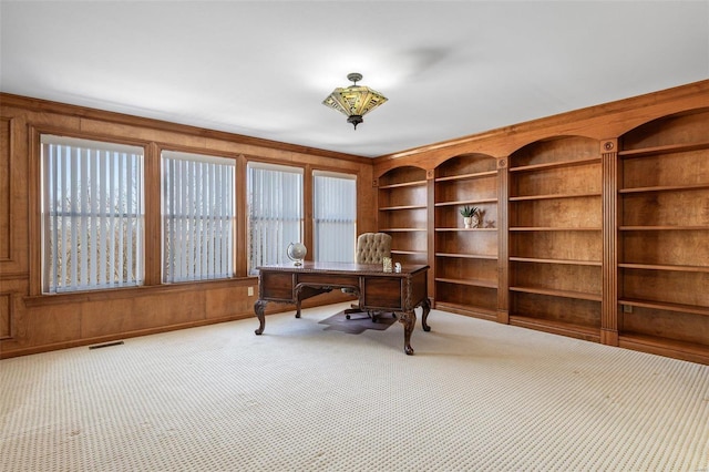 office featuring carpet, plenty of natural light, wooden walls, and visible vents