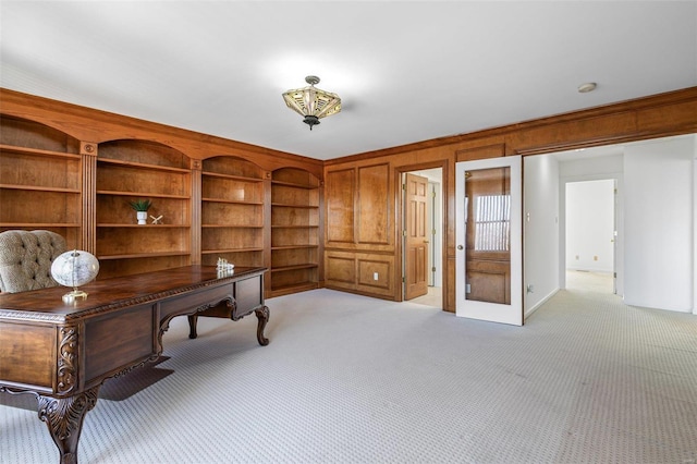 office space featuring built in shelves, wood walls, and light colored carpet