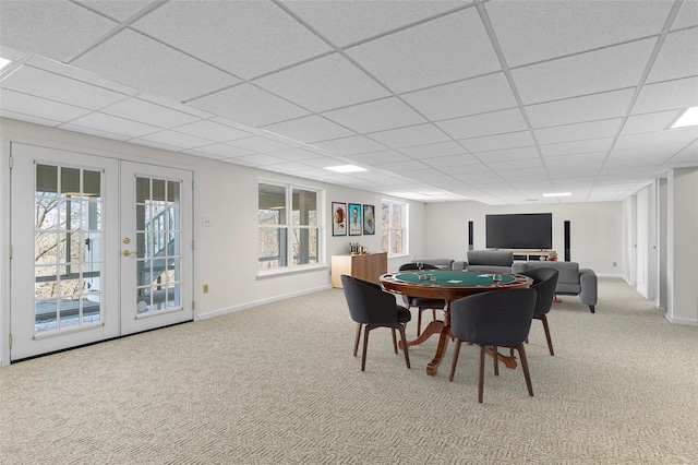 carpeted dining space with french doors, a drop ceiling, and baseboards