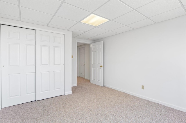 unfurnished bedroom with a paneled ceiling, carpet flooring, and baseboards