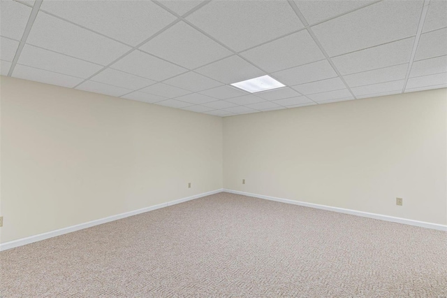 carpeted empty room with a drop ceiling and baseboards