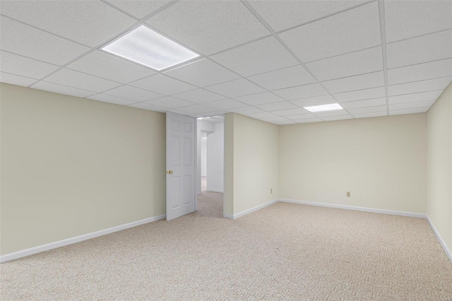 finished below grade area with light carpet, baseboards, and a paneled ceiling