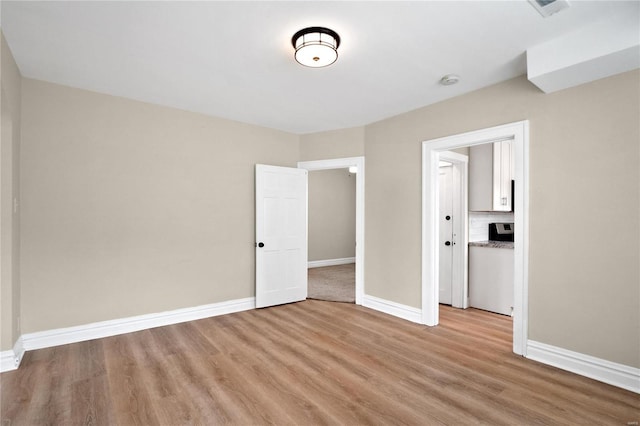 unfurnished bedroom featuring light wood-type flooring, visible vents, and baseboards