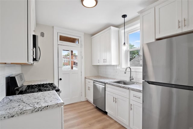 kitchen featuring tasteful backsplash, light wood-style flooring, appliances with stainless steel finishes, a sink, and plenty of natural light