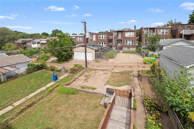 view of yard featuring a garage, a vegetable garden, fence, and a residential view