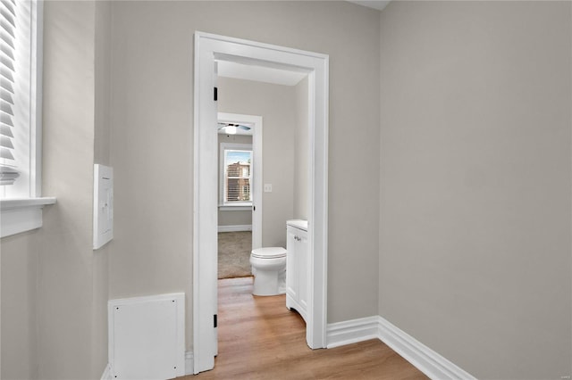 hallway with light wood-type flooring and baseboards