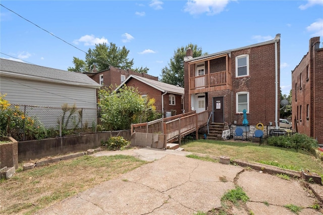 view of front of home with brick siding, a front lawn, fence, and a balcony