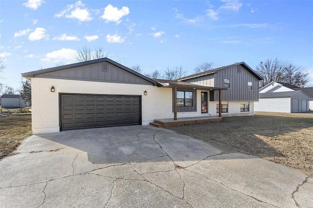 view of front facade featuring a garage, concrete driveway, brick siding, and board and batten siding