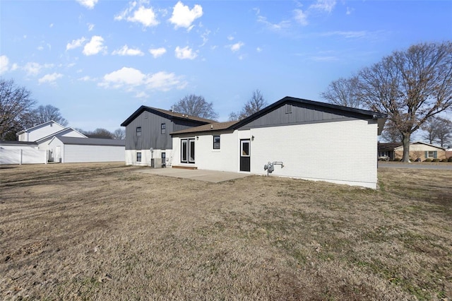 rear view of property with a yard, brick siding, and a patio