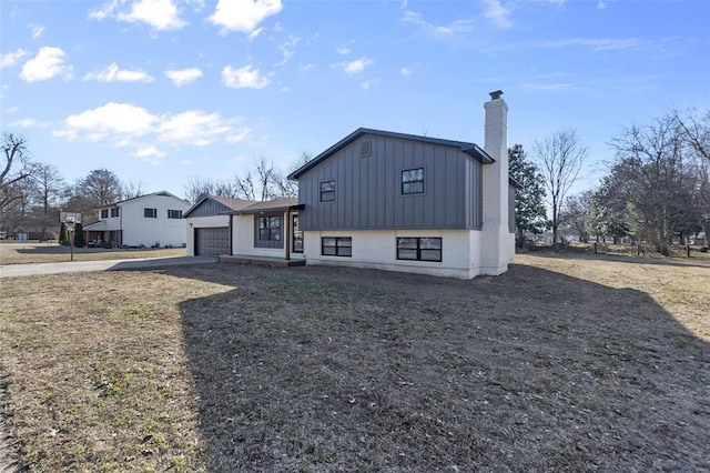 view of front of property with brick siding, a chimney, an attached garage, board and batten siding, and driveway