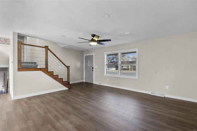 unfurnished living room with baseboards, visible vents, a ceiling fan, wood finished floors, and stairs