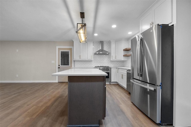 kitchen featuring stainless steel appliances, white cabinetry, a center island, wall chimney exhaust hood, and tasteful backsplash