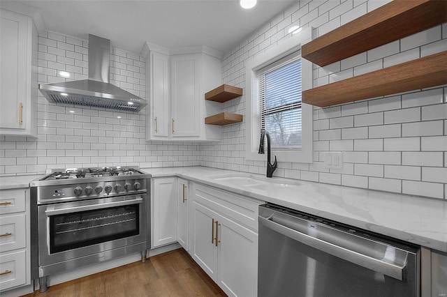 kitchen featuring wall chimney exhaust hood, a sink, stainless steel appliances, open shelves, and backsplash