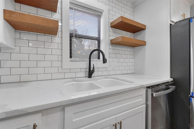 kitchen featuring open shelves, backsplash, appliances with stainless steel finishes, white cabinetry, and a sink