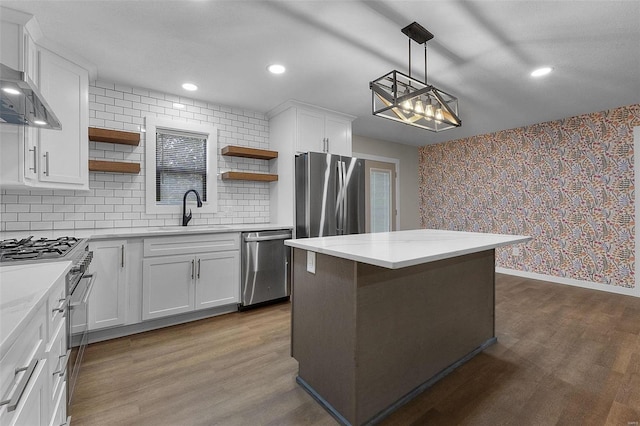 kitchen featuring wallpapered walls, dark wood-type flooring, stainless steel appliances, open shelves, and a sink