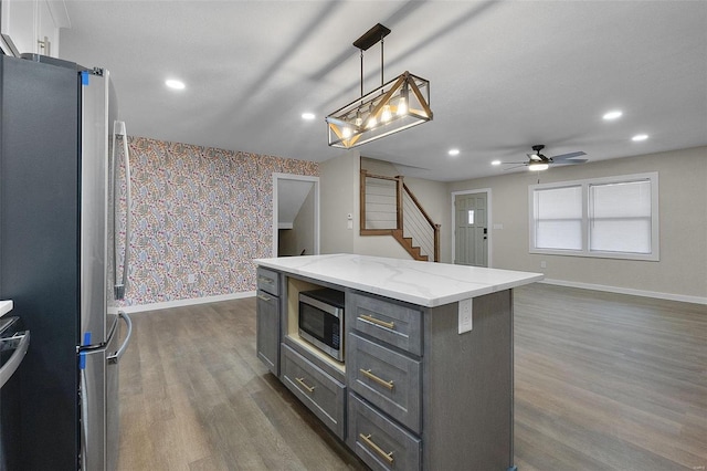 kitchen with wallpapered walls, baseboards, dark wood-type flooring, stainless steel appliances, and gray cabinetry