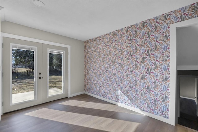 spare room with baseboards, french doors, wood finished floors, and wallpapered walls