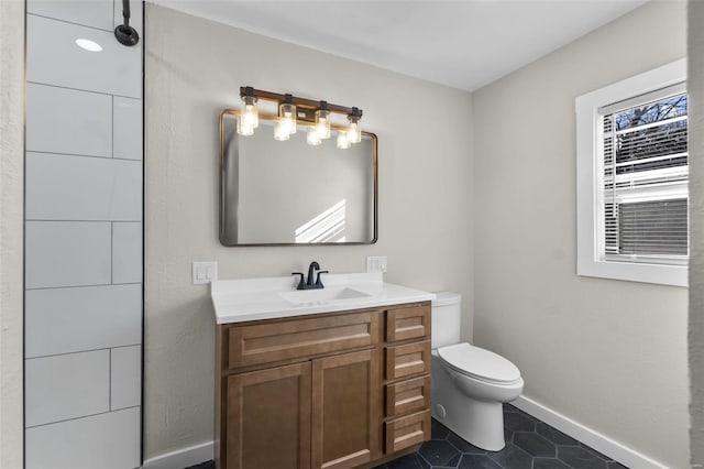 bathroom featuring baseboards, vanity, toilet, and tile patterned floors