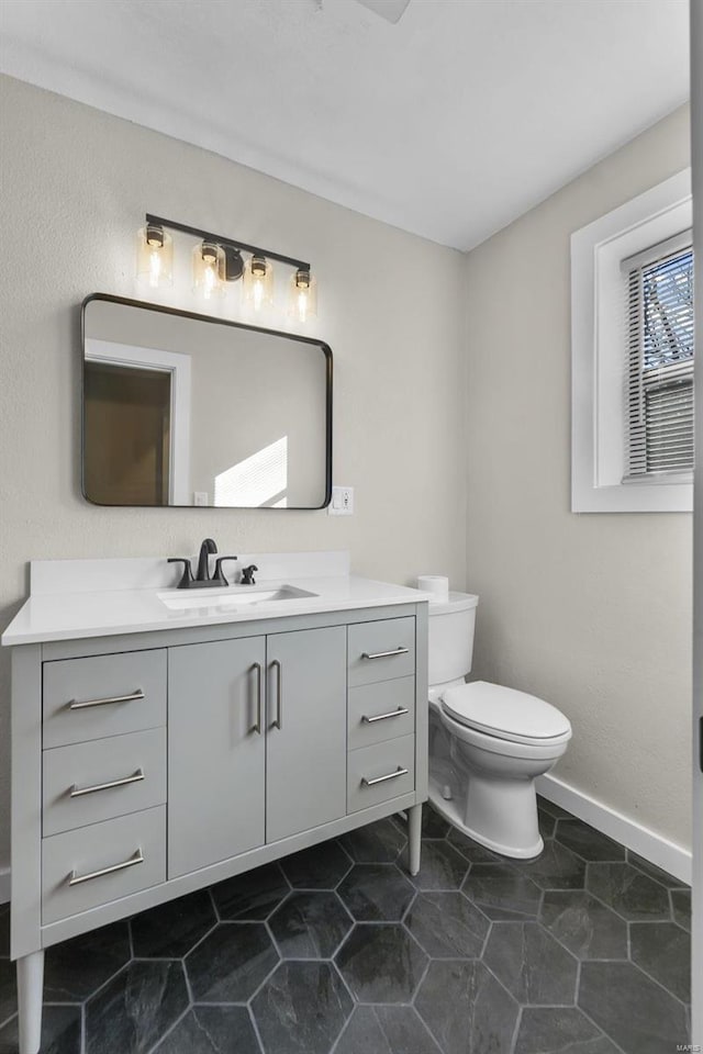 bathroom with baseboards, vanity, and toilet