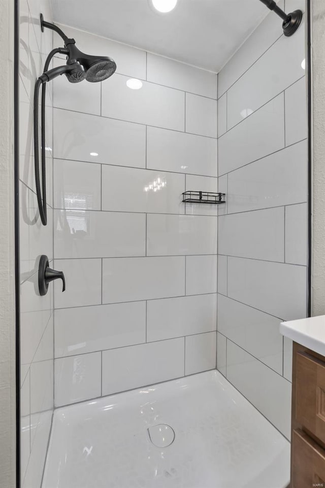 bathroom featuring tiled shower and vanity