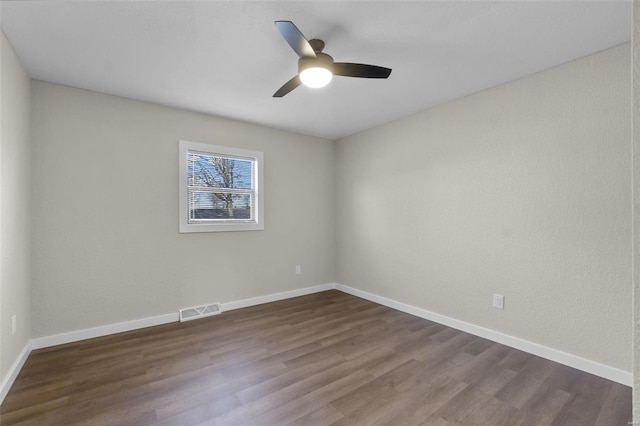 unfurnished room featuring dark wood-style floors, visible vents, ceiling fan, and baseboards