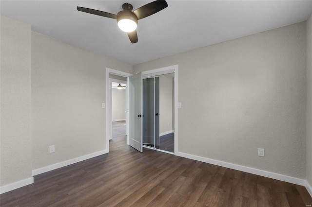 empty room with ceiling fan, dark wood-type flooring, and baseboards