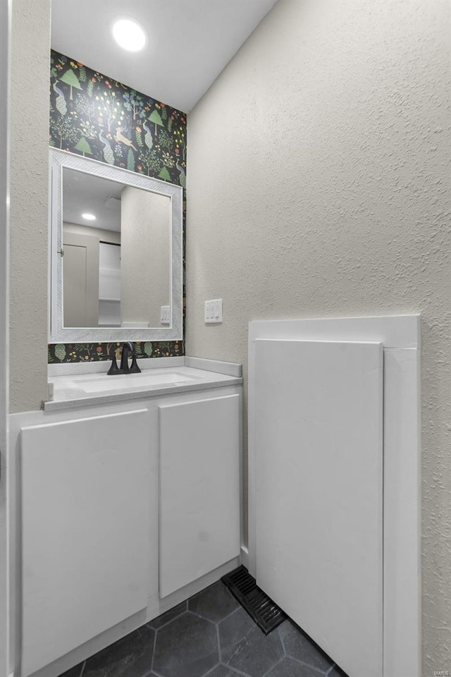 bathroom with a textured wall, tile patterned flooring, and vanity