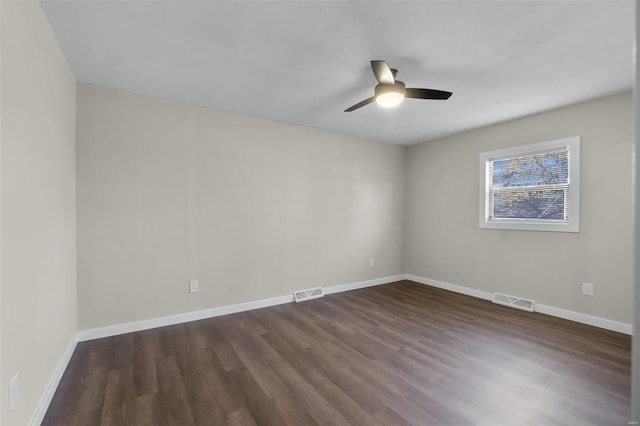 empty room with dark wood finished floors, visible vents, and baseboards