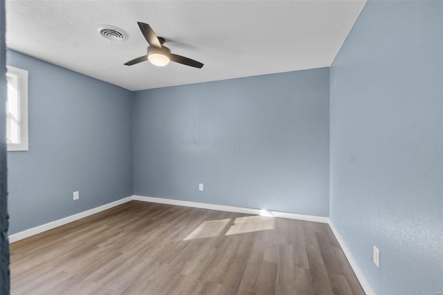 spare room with visible vents, ceiling fan, baseboards, and wood finished floors