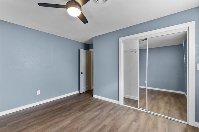 unfurnished bedroom with a closet, wood finished floors, a ceiling fan, and baseboards