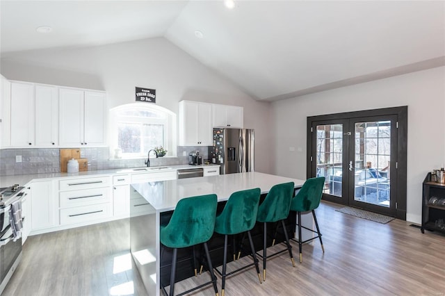 kitchen featuring a kitchen island, appliances with stainless steel finishes, a kitchen breakfast bar, french doors, and a sink