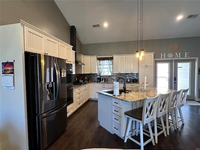 kitchen featuring tasteful backsplash, visible vents, vaulted ceiling, light stone countertops, and black appliances