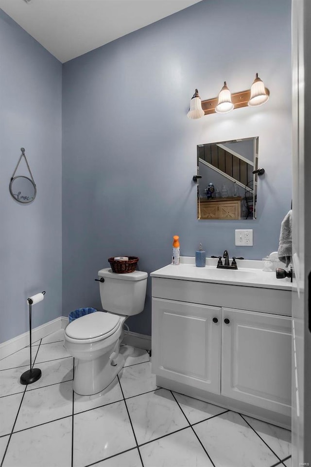 bathroom with marble finish floor, toilet, vanity, and baseboards