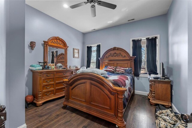 bedroom featuring visible vents, baseboards, dark wood finished floors, and a ceiling fan