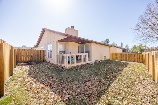 rear view of property with a fenced backyard and a chimney