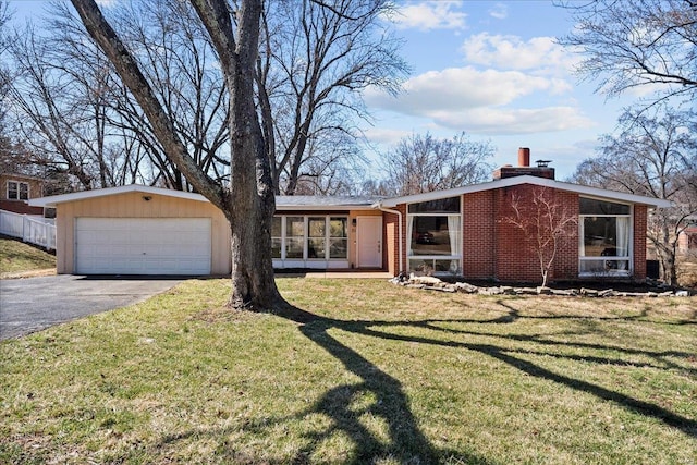 mid-century home with a front yard, brick siding, a detached garage, and a chimney